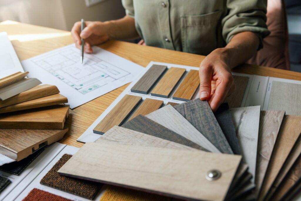 Nahaufnahme eines Planungstischs mit Bodenmustern aus Holz und Laminat neben Wohnungsplan – Materialien passend zu Polsterbetten
