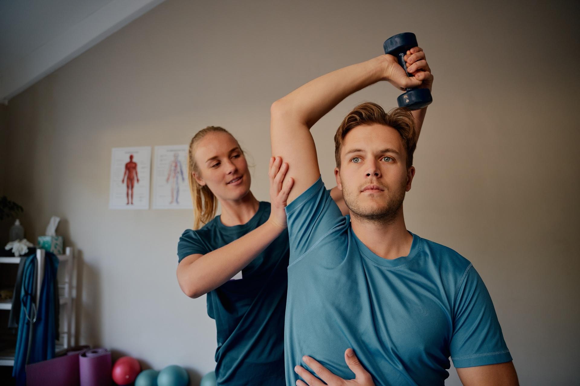 Physiotherapeutin betreut Training mit Hantel | Therapieliegen